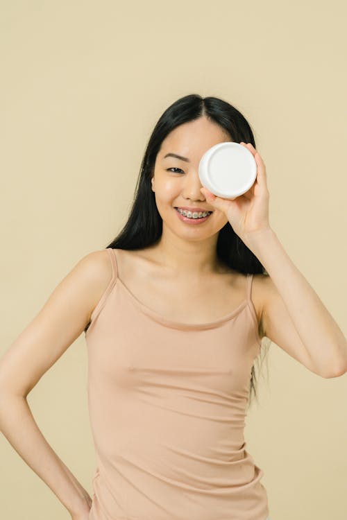 Smiling woman holding aloft cosmetic container