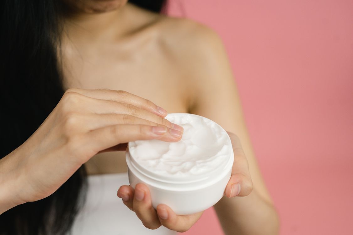 Mano aplicando crema hidratante en cuerpo