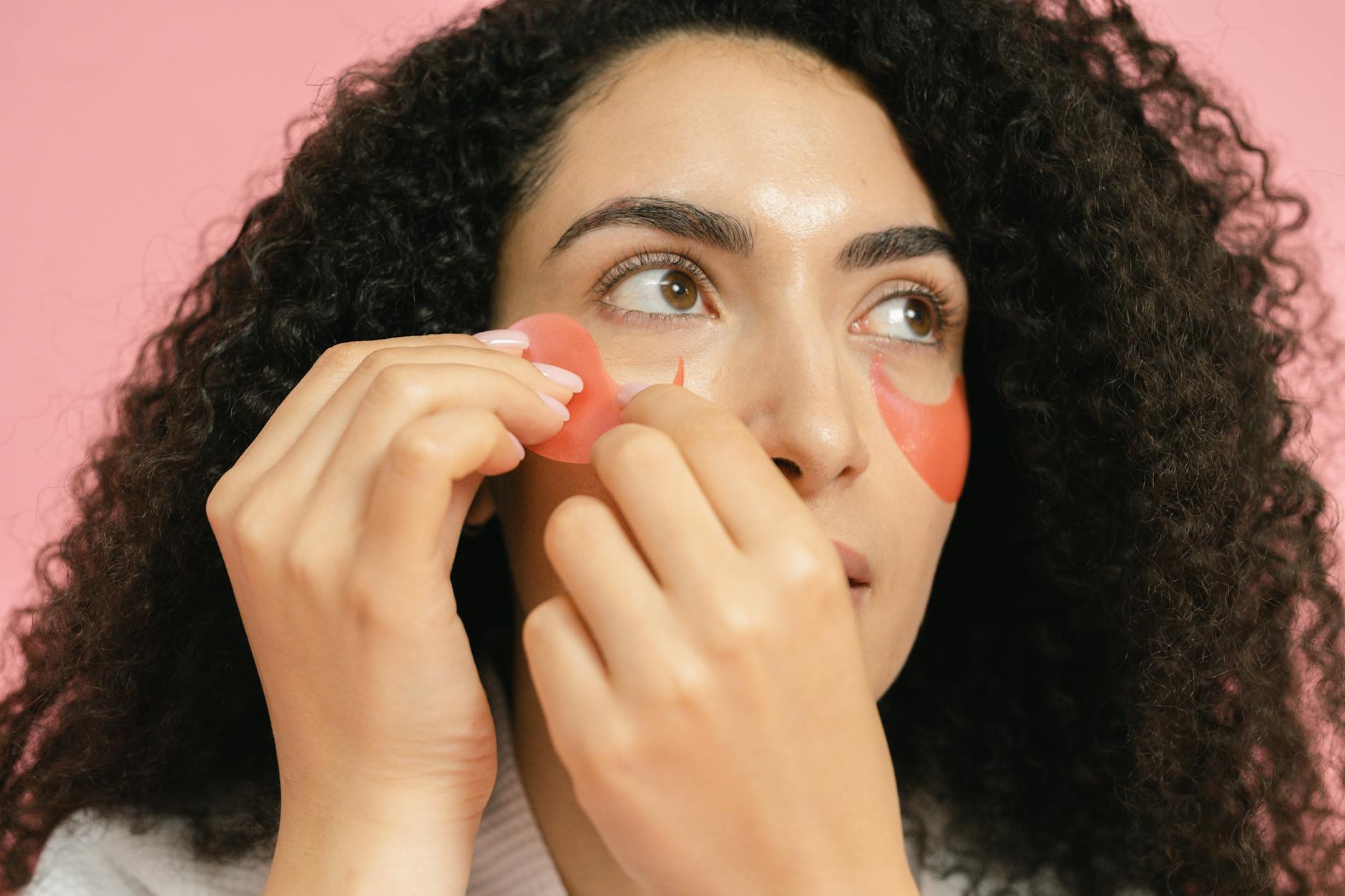 Woman putting on red cosmetic pads under her eyes