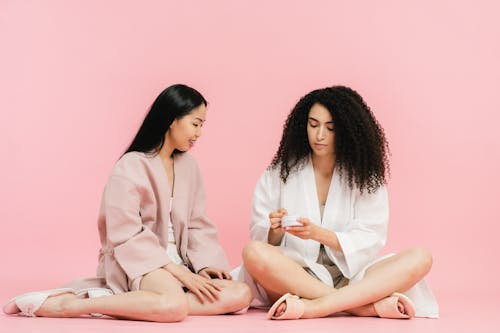 Two women in robes and slippers sitting