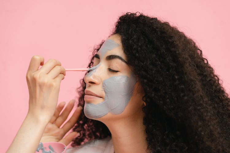 Womans Hand Painting Her Friends Nose With Gray Clay Mask