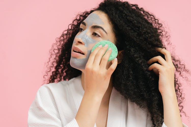 Woman Removing A Face Mask With A Sponge