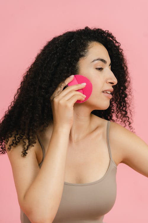 Woman in beige top putting on face powder with cosmetic sponge pad