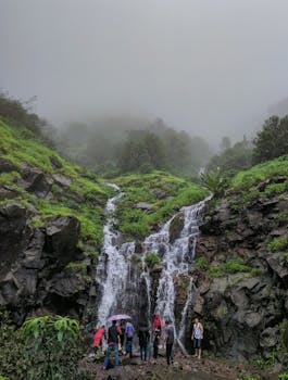 一群人在薄雾缭绕的岩石间探索瀑布，非常适合自然与冒险主题