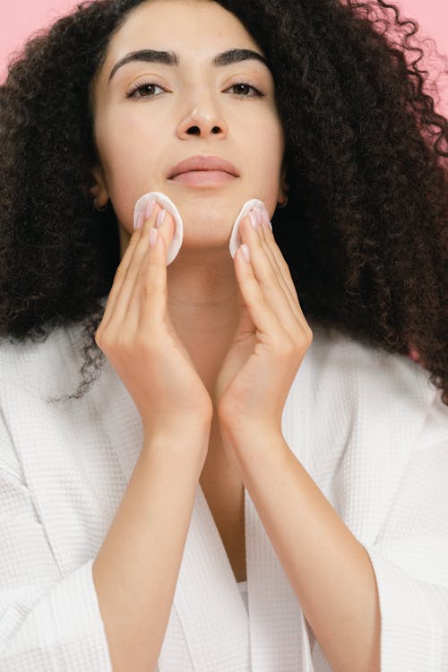 Woman putting cosmetic on with two cotton pads