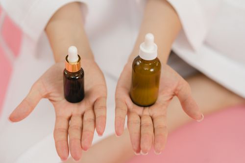Free Close-up of hands holding two cosmetic dropper bottles for skincare routine. Stock Photo