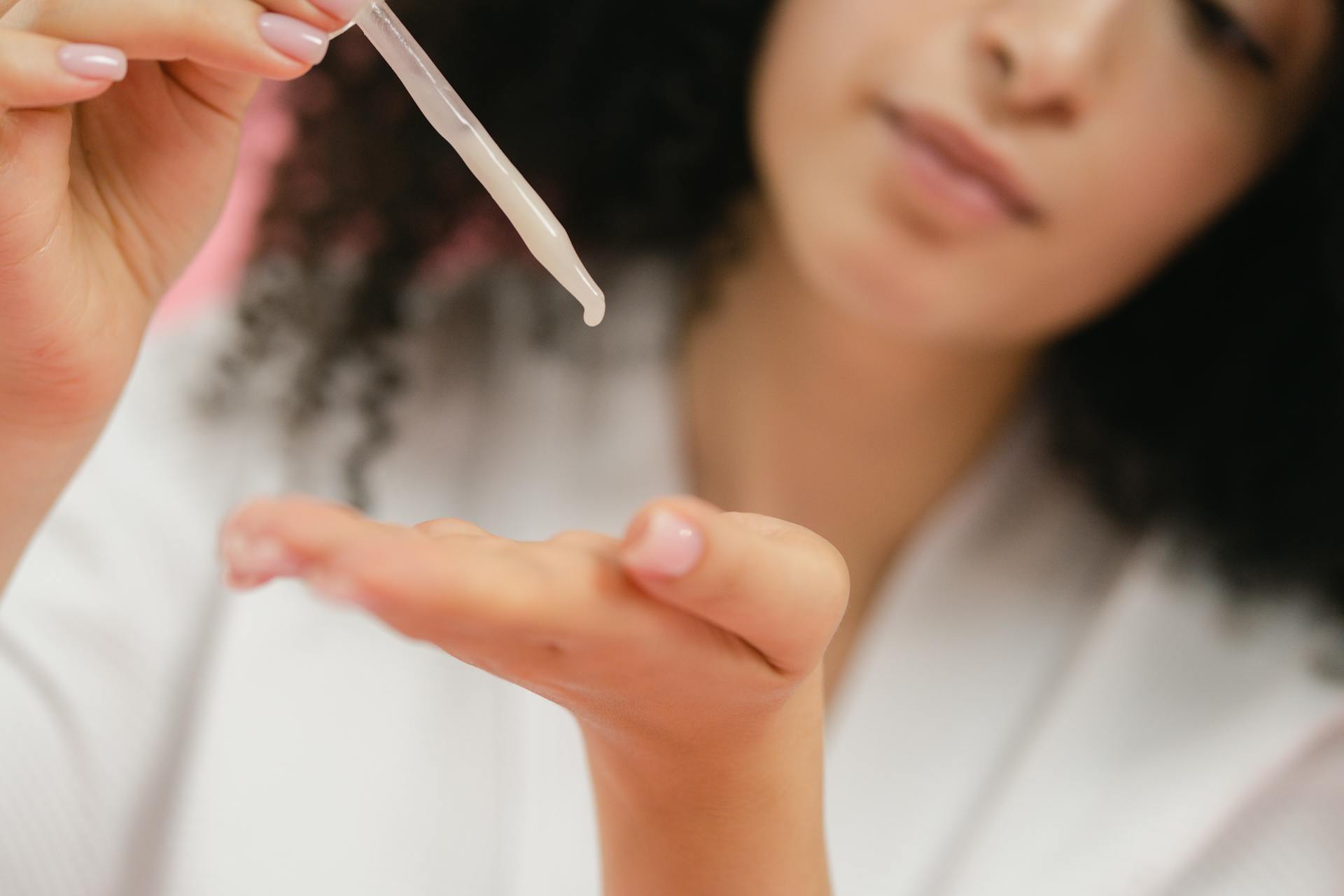 Woman Applying Cream on Hand with Pipette