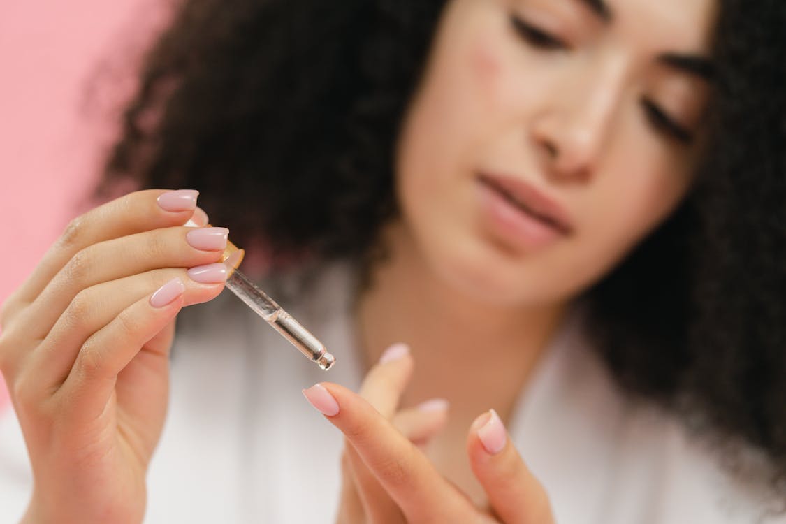 Free Close-up of Woman Putting Serum on Her Finger with the Use of a Pipette Stock Photo
