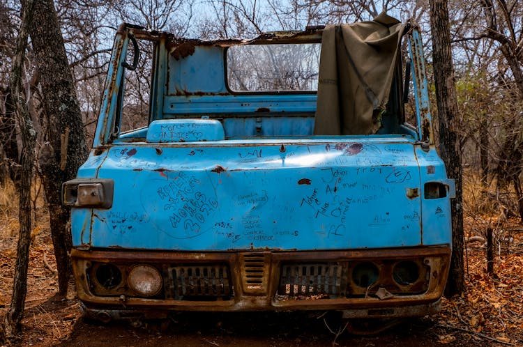 A Blue Abandoned Car Parked With Vandalism