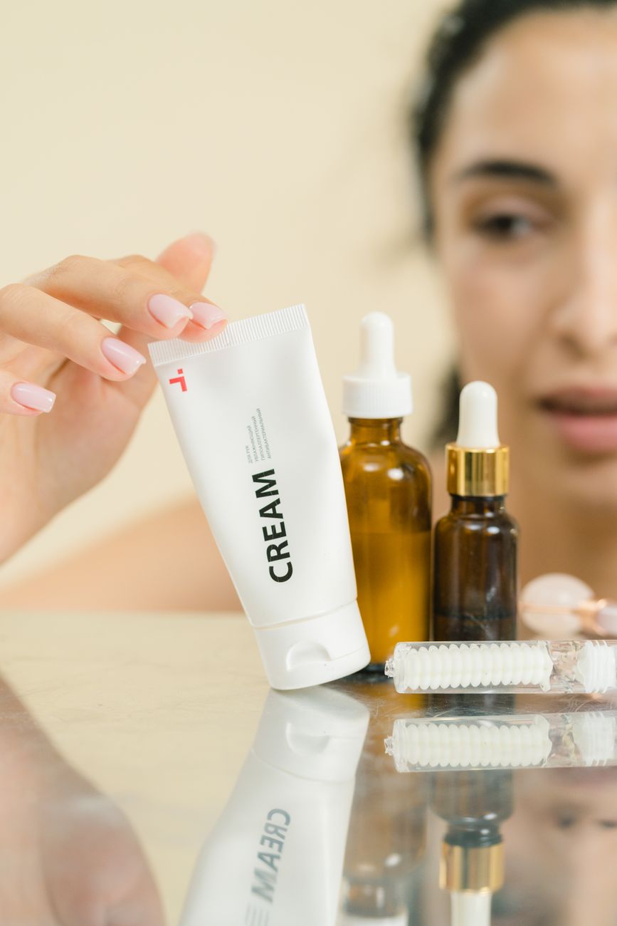 A woman selects skincare products including cream and serums, reflecting self-care.