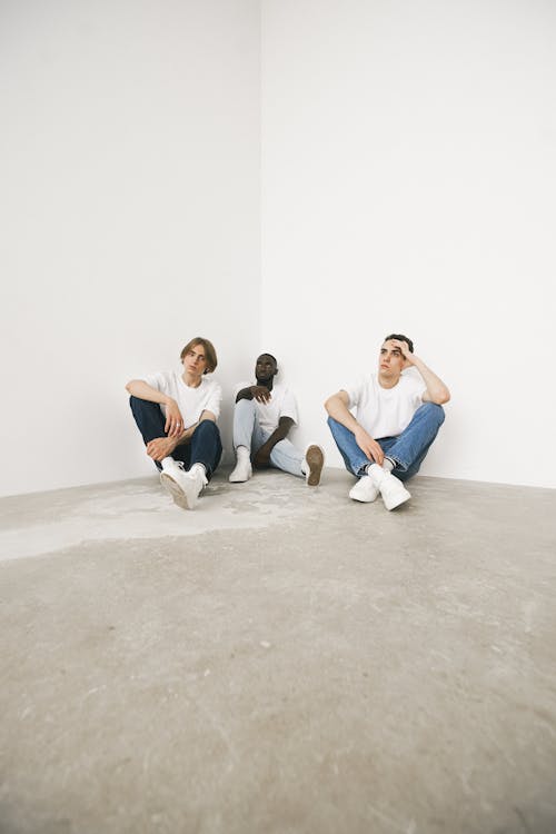 Free Men Wearing White Shirts and Denim Pants Sitting on the Floor Stock Photo