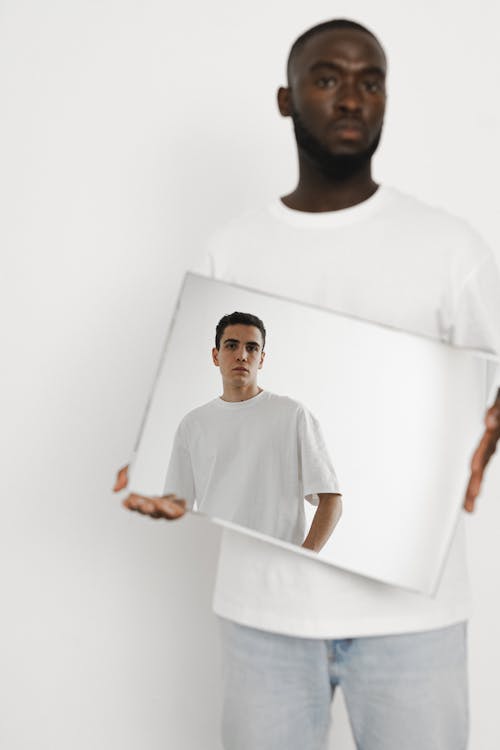 A Man Holding a Mirror with a Reflection of a Man in White Shirt