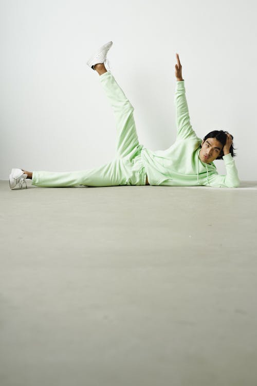 A Man Wearing a Green Hoodie and Green Pants Lying Down on the Floor