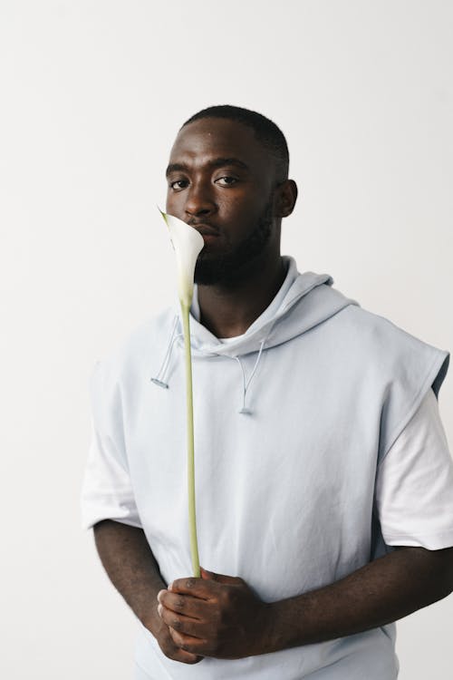 Close-Up Shot of a Man Holding a White Flower on White Background