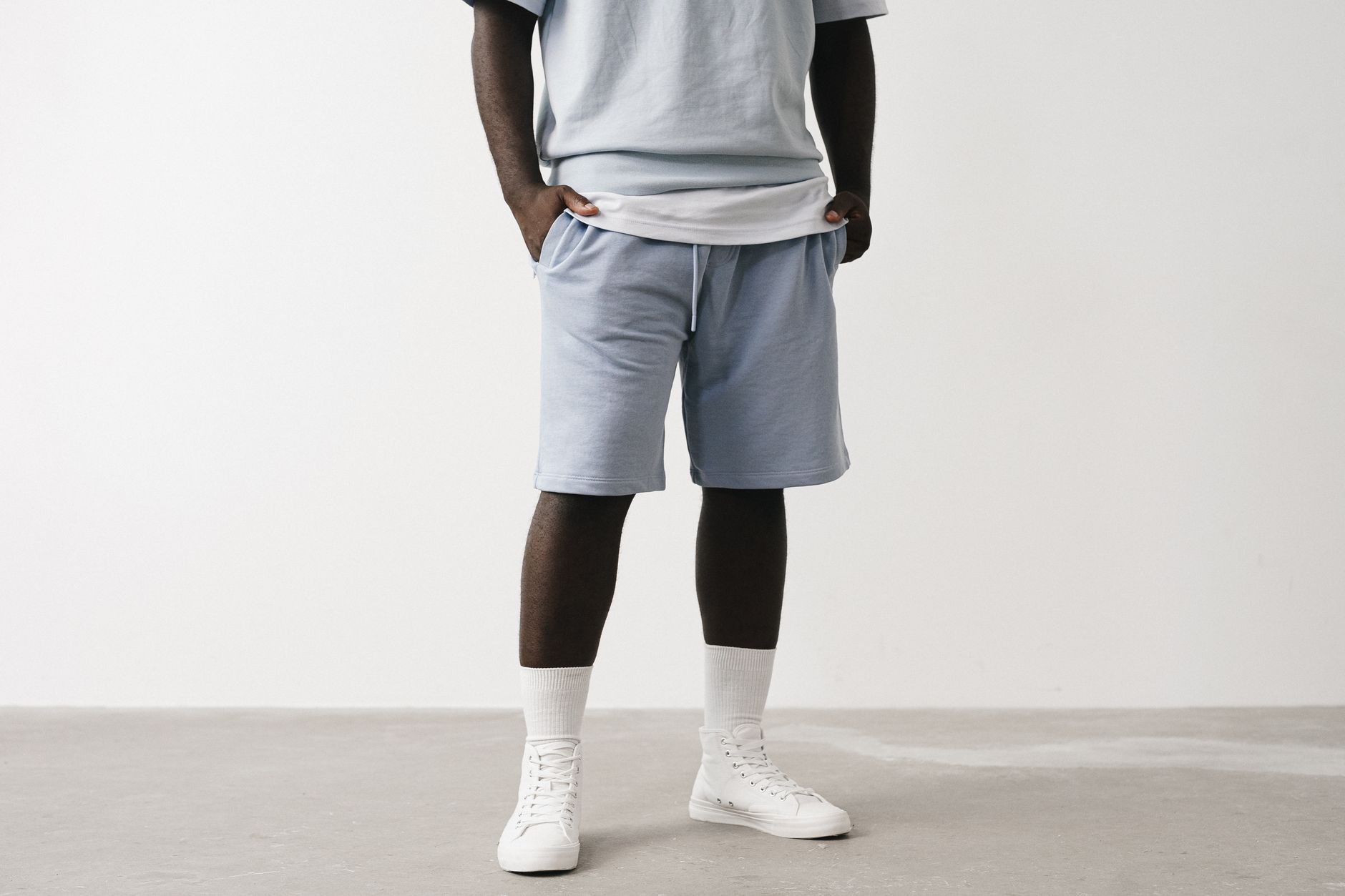 Pantalon court streetwear homme bleu chiné porté avec sneakers blanches, tenue urbaine minimaliste