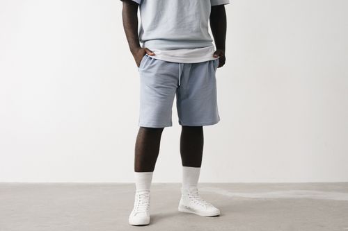 Free Stylish casual outfit featuring light blue shorts and white sneakers. Stock Photo