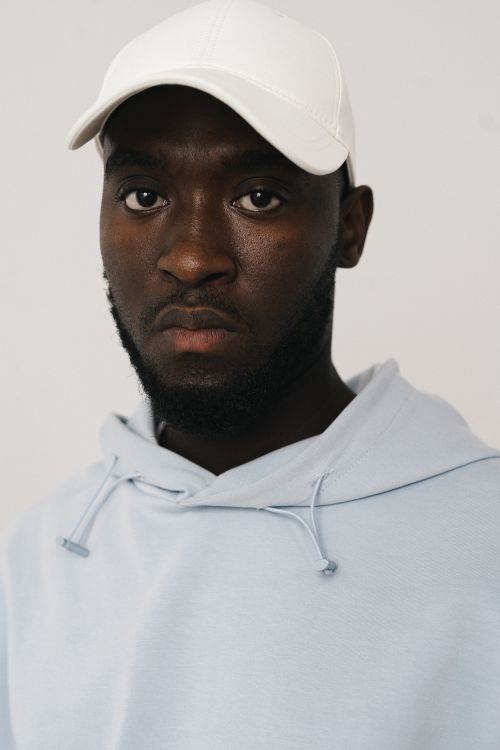 Free Close-up portrait of a man with a beard wearing a white cap and hoodie. Stock Photo
