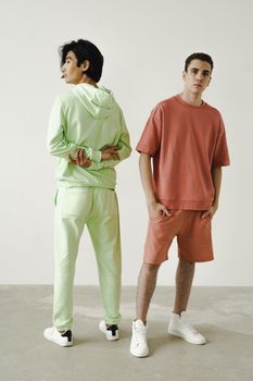 Two men modeling stylish casual wear in a minimalist studio backdrop, showcasing fashion and comfort.