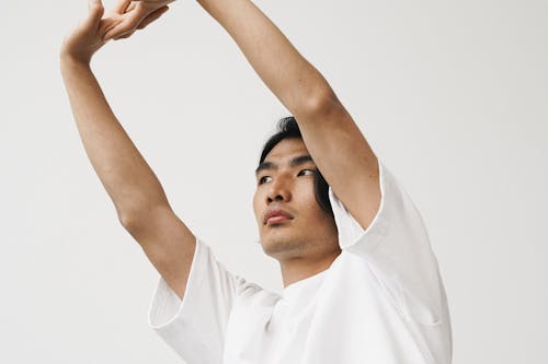 A Low Angle Shot of a Man in White Shirt Raising His Hands