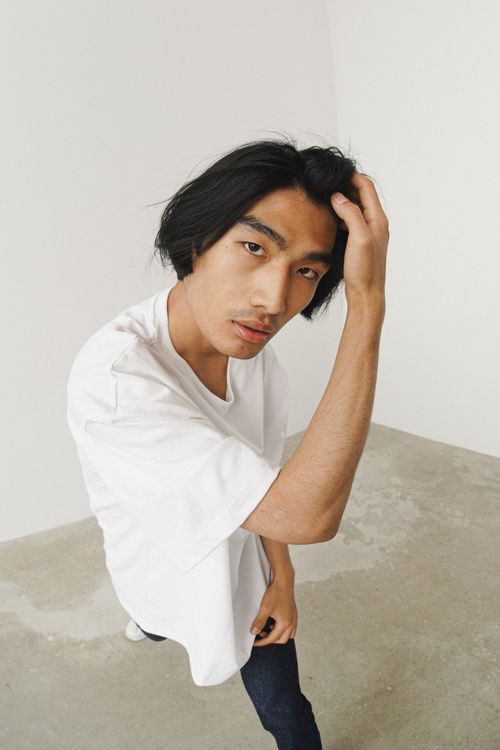 Free High angle shot of a man in a white shirt standing on a concrete floor indoors, exuding minimalist style. Stock Photo