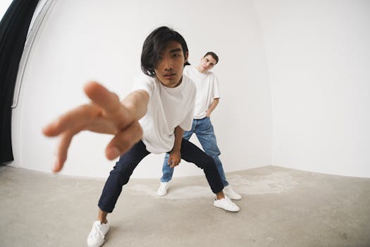 Two men in white shirts and jeans striking dynamic poses in a minimalist indoor setting.
