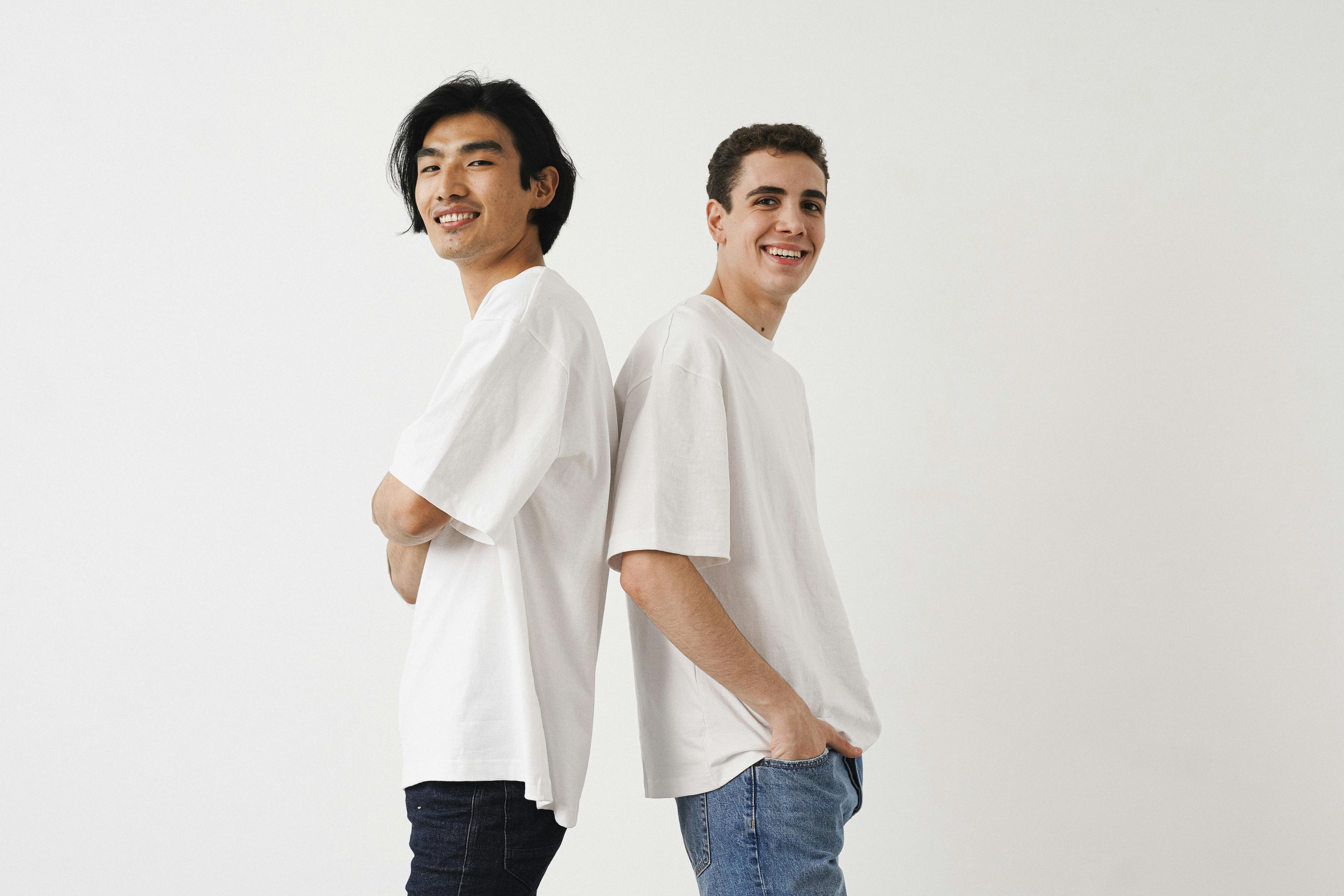 Young Men in T-shirts and Jeans Standing Back to Back and Smiling