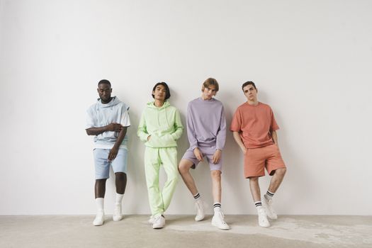 Group of stylish men in colorful pastel outfits posing against a white wall. — photo by SHVETS production