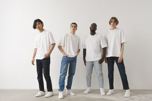 Free Four diverse young men in casual outfits posing against a white wall, embodying modern style and diversity. Stock Photo