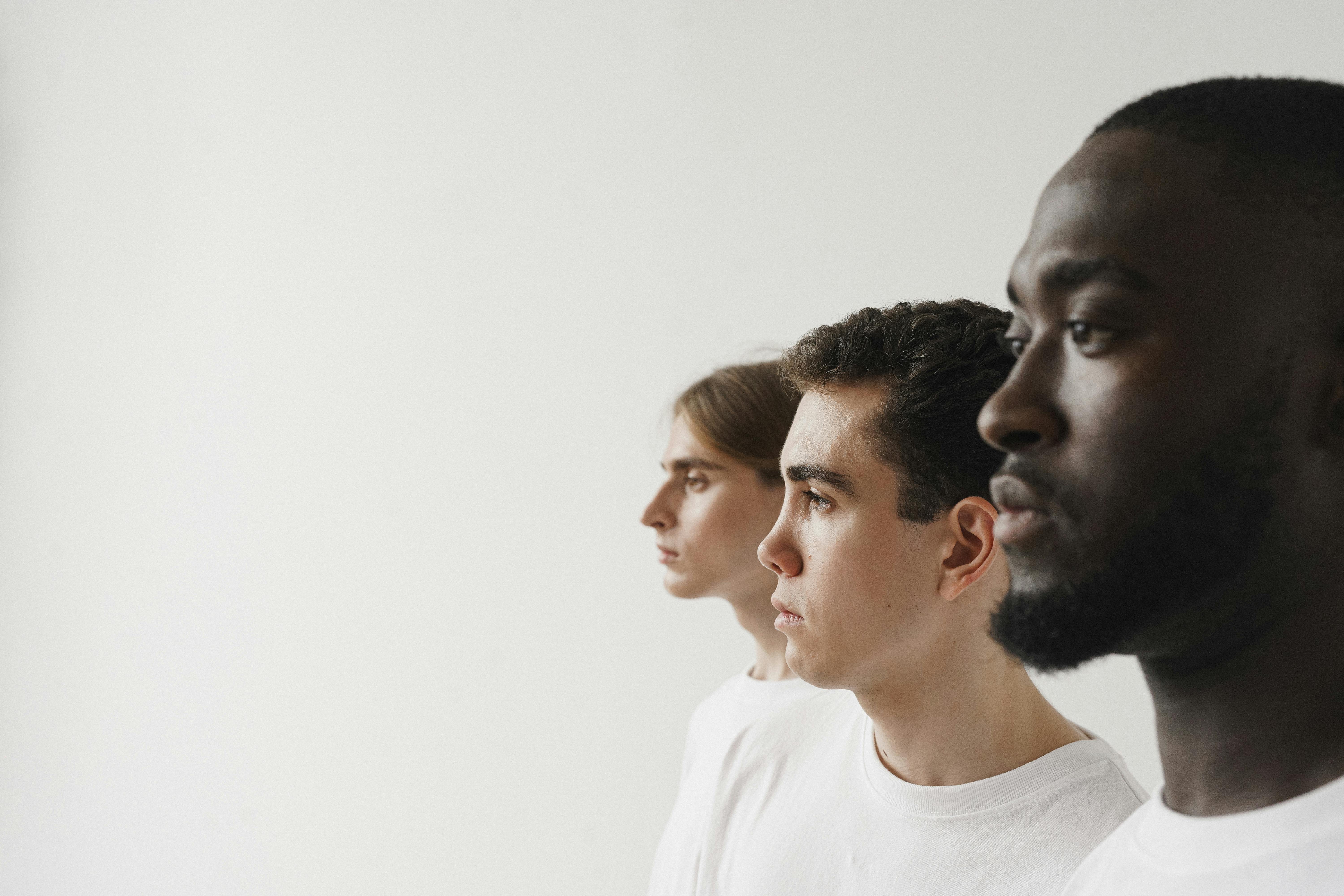 A diverse group of men in profile against a plain white background, showcasing unity.