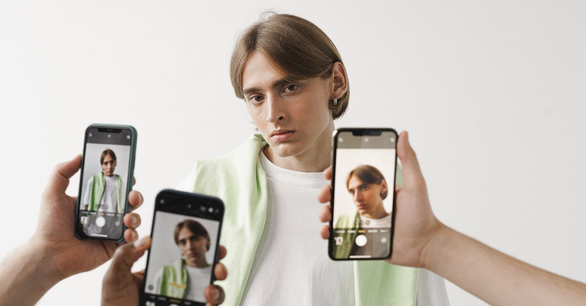 A man in a white shirt is being photographed with multiple smartphones against a plain background.