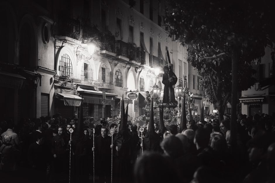 Una vibrante procesión de Semana Santa por la noche en Carmona, España, con figuras religiosas y una gran multitud.