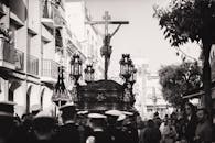 这张黑白照片拍摄于西班牙卡莫纳的宗教游行，画面中有基督雕像和人群
