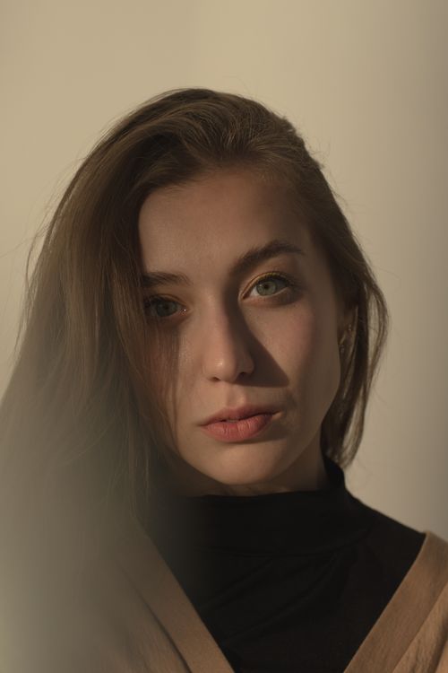 Free A close-up portrait of a young woman with long hair in soft lighting, evoking introspection. Stock Photo
