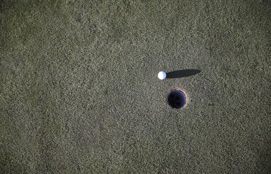 修剪整齐的高尔夫球场果岭上，一个靠近球洞的高尔夫球特写镜头