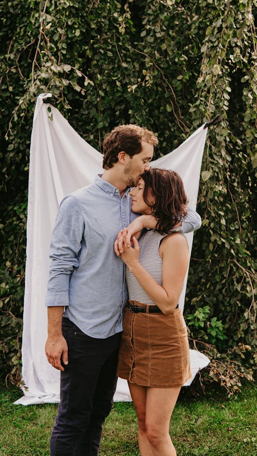 Man in Dress Shirt Kissing Woman on her Forehead