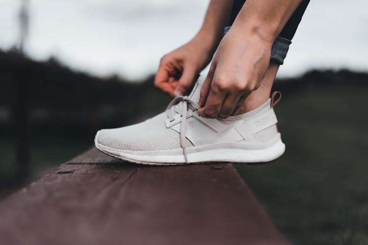 A Person Tying Shoelace Of A Sneaker