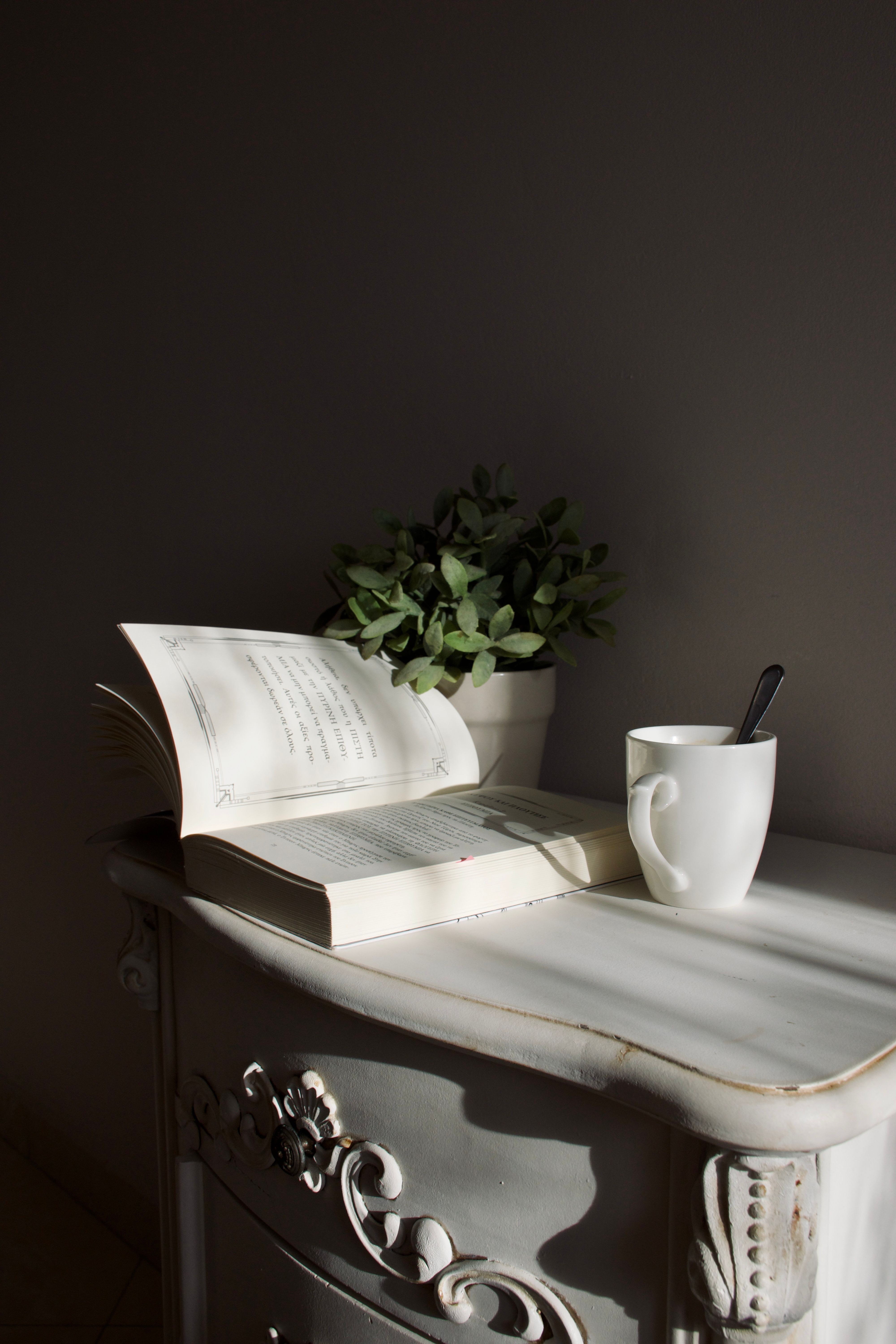 small wooden dresser in a corner used as a coffee bar with mugs and coffee maker on top