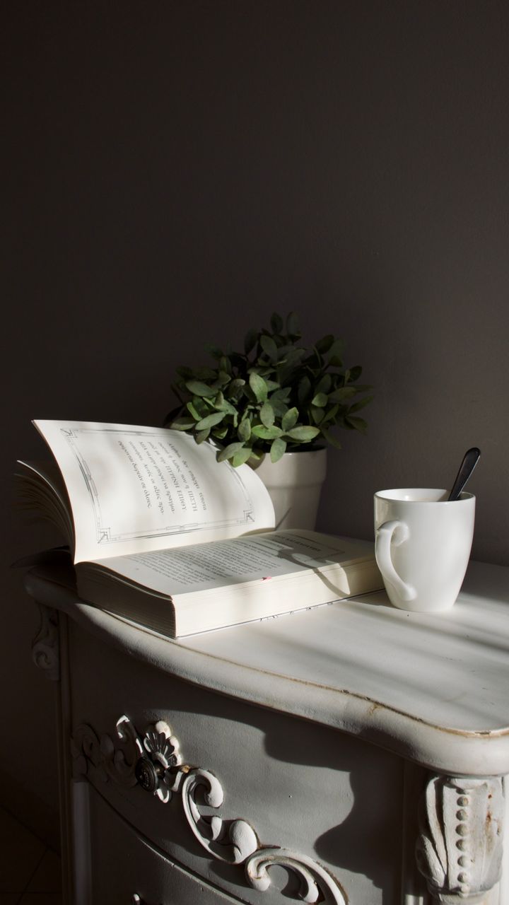 small wooden dresser in a corner used as a coffee bar with mugs and coffee maker on top