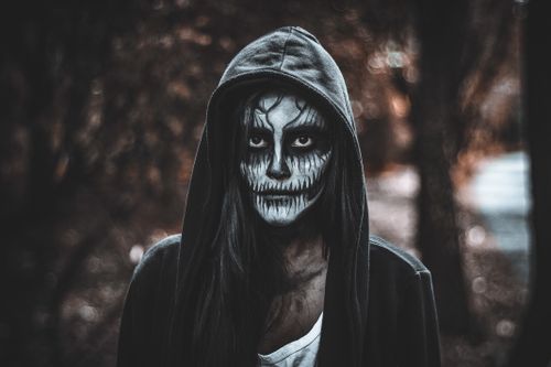 Free A haunting portrait featuring an adult woman with Catrina makeup in a mysterious forest setting. Stock Photo