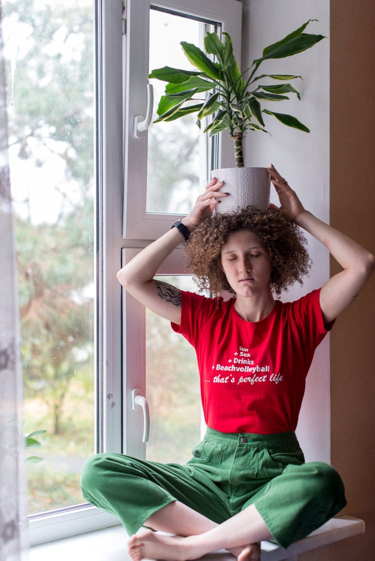 Woman Holding Plant In Vase On Head