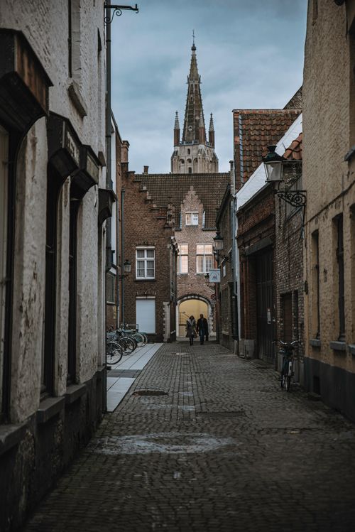 Free Scenic cobblestone street view in Bruges, featuring medieval architecture and St. Salvator's Cathedral. Stock Photo