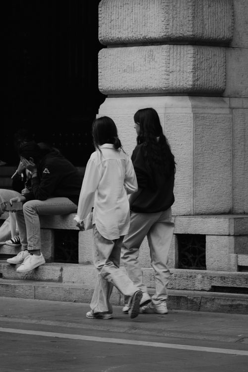 Free Black and white street photo capturing people walking beside an architectural structure. Stock Photo