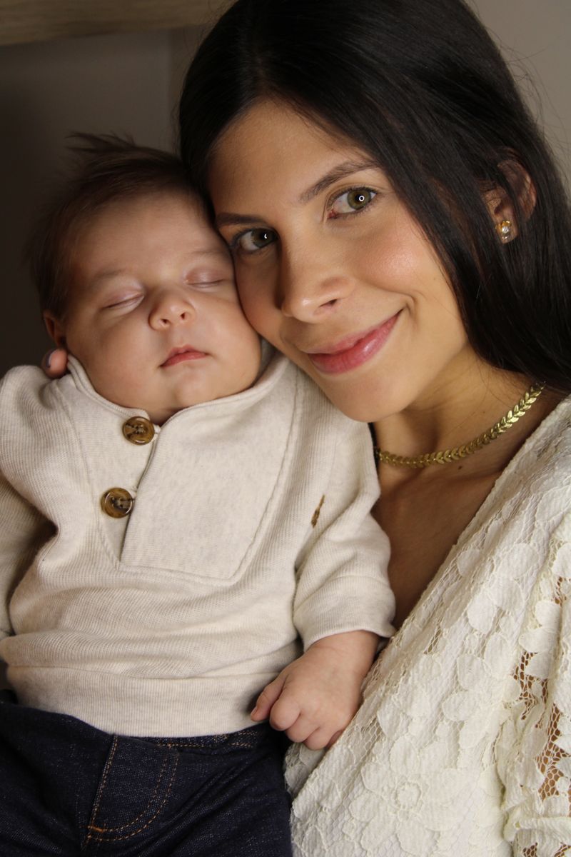 Smiling mother holding her sleeping newborn baby