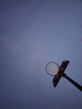 Low angle view of a basketball hoop silhouetted against a starry night sky in Toulouse.