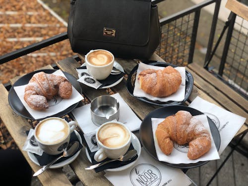 Free Servings of Croissants and Latte on Wooden Table Stock Photo