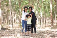 Three sisters smiling and posing together in a serene Cambodian forest setting.