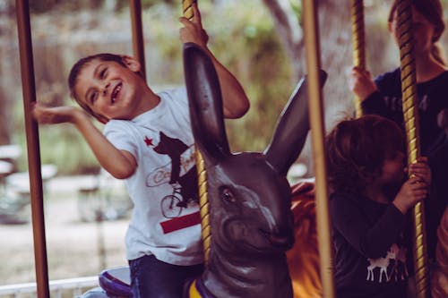 Free Boy in White T-shirt Riding Carousel Stock Photo