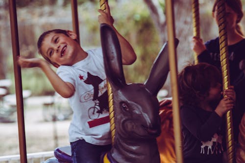 Boy in White T-shirt Riding Carousel