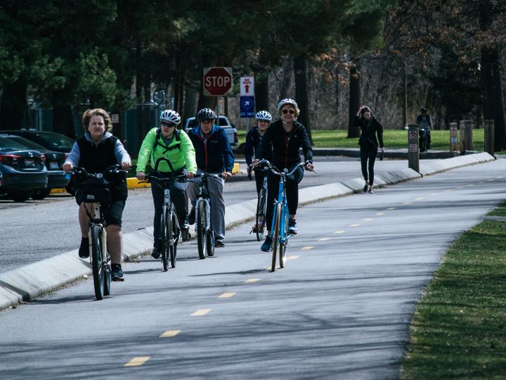 A diverse group of cyclists enjoying a ride on a sunny outdoor bike path.