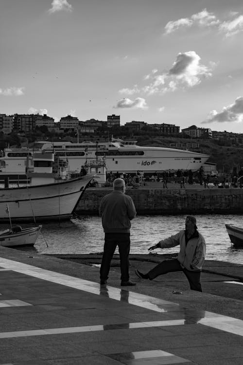 Grayscale Photo of Two Men Standing on Pier